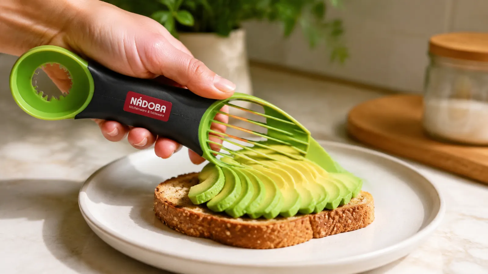 A hand fanning out neatly sliced avocado onto a piece of toast using the slicing comb end of the tool