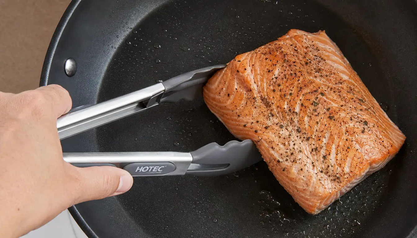 A hand holding HOTEC tongs wide to lift a piece of salmon without tearing the skin
